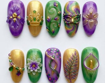 May include: A collection of ten intricately designed nail art samples. Each nail features a different design, including floral patterns, a crown, a mask, and swirling colors, in shades of gold, green, purple, and yellow. The nails are oval-shaped and appear to be gel or acrylic.