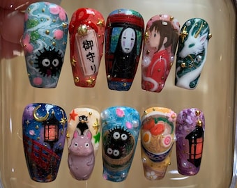 May include: A set of ten press-on nails featuring detailed hand-painted designs inspired by Studio Ghibli films. The artwork includes characters like No-Face, Totoro, and soot sprites, alongside motifs such as ramen, lanterns, and cherry blossoms, accented with small gold studs and pearls.