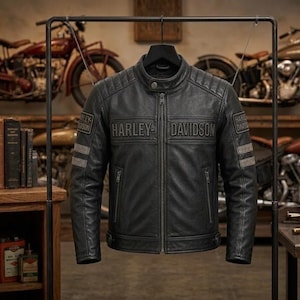 Op de afbeelding: Een zwarte leren motorjas met een opstaande kraag met drukknoopsluiting, een ritssluiting over de volledige lengte en doorgestikte schouderdetails. Op de borst staat de in reliëf aangebrachte tekst Harley-Davidson, met bijpassende patches.