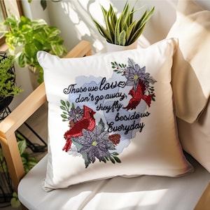 May include: White square pillow with embroidered red cardinals, purple flowers, and green leaves. The pillow has the text "Those we love don't go away, they fly beside us everyday."