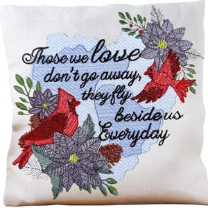 Könnte beinhalten: Cremefarbenes Zierkissen mit gesticktem Design. Es zeigt rote Kardinäle, graue Blumen und den Text "Those we love don't go away, they fly beside us everyday" in schwarzer Schrift. Enthält grünes Laub und einen blauen Hintergrund.