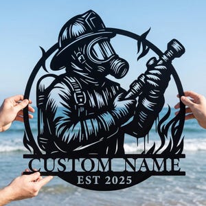 Könnte beinhalten: Schwarze Metall-Wandkunst, die einen Feuerwehrmann mit Gasmaske und Helm zeigt, der einen Schlauch hält. Das Design umfasst Flammen und einen kreisförmigen Rahmen. Der Text unten lautet "CUSTOM NAME EST 2025".