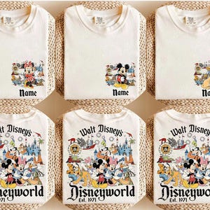 May include: Off-white t-shirts featuring Disney characters. Some shirts have a small graphic with Minnie Mouse, Mickey Mouse, or Simba. Other shirts display a larger graphic with multiple characters and the text "Walt Disney's Disneyworld Est. 1971."