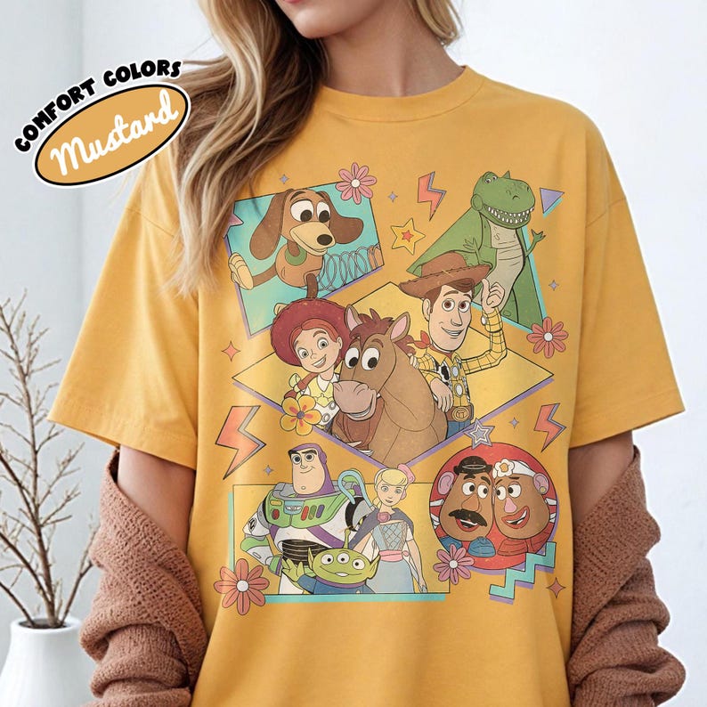 Puede incluir: Camiseta de color mostaza con un gr&aacute;fico de personajes de la pel&iacute;cula de animaci&oacute;n Toy Story. El dise&ntilde;o incluye im&aacute;genes de Woody, Buzz Lightyear y otros personajes. La camiseta tiene las palabras "Comfort Colors" y "Mustard" impresas.