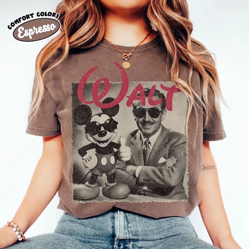 K&ouml;nnte beinhalten: Ein braunes T-Shirt mit einem Retro-Grafik von Mickey Mouse und Walt Disney, beide mit Sonnenbrille. Das Wort "WALT" ist rot &uuml;ber dem Bild gedruckt. Das Shirt hat die Worte "COMFORT COLORS Espresso" oben links aufgedruckt.