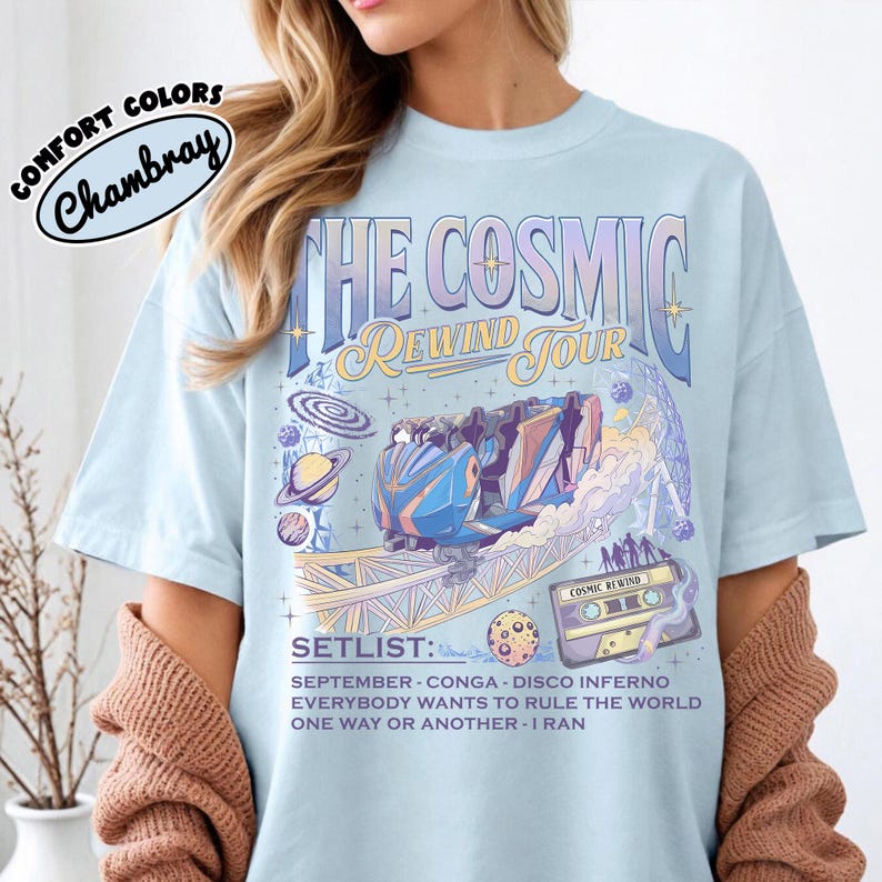 K&ouml;nnte beinhalten: Hellblaues T-Shirt mit einem Grafikdesign f&uuml;r "The Cosmic Rewind Tour". Das Design zeigt eine Achterbahn, Planeten und den Text "SETLIST: SEPTEMBER - CONGA - DISCO INFERNO - EVERYBODY WANTS TO RULE THE WORLD - ONE WAY OR ANOTHER - I RAN."