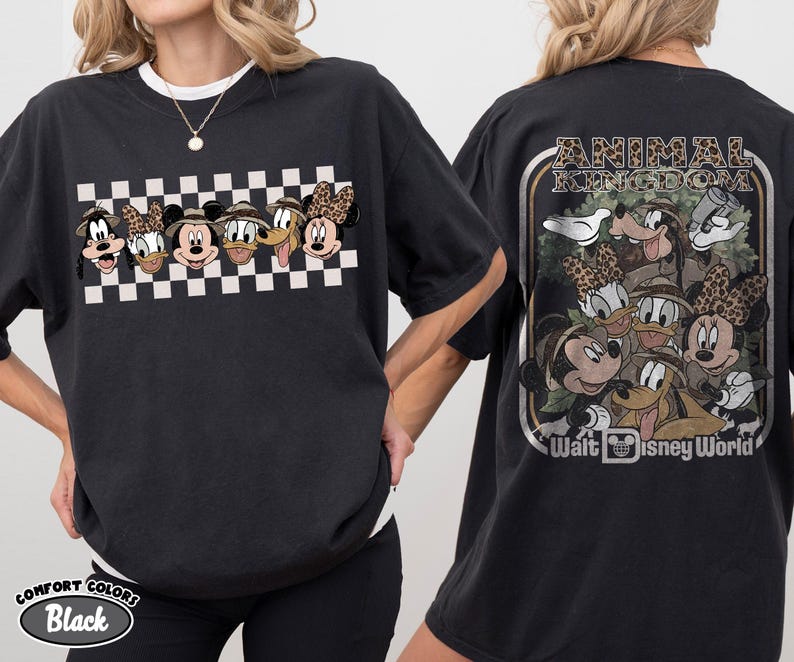 K&ouml;nnte beinhalten: Schwarzes T-Shirt mit einer Grafik von Disney-Figuren, darunter Mickey, Minnie, Donald, Goofy und Pluto, in Safari-Kleidung. Das Frontdesign ist vor einem schwarz-wei&szlig;en Schachbrettmuster platziert. Auf der R&uuml;ckseite des Shirts steht der Text "ANIMAL KINGDOM" und "Walt Disney World".