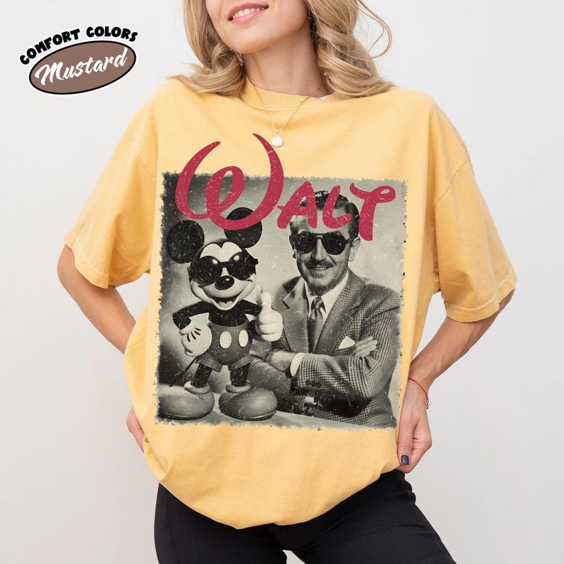 K&ouml;nnte beinhalten: Senfgelbes T-Shirt mit einem Vintage-Motiv von Mickey Mouse und Walt Disney mit Sonnenbrille. Das Wort "WALT" steht in roter Schrift &uuml;ber dem Bild. Das T-Shirt ist mit "Comfort Colors" gekennzeichnet.