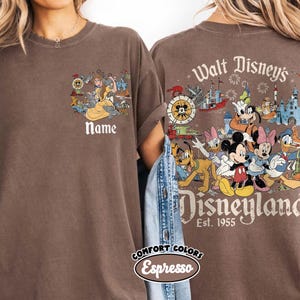 Peut inclure: T-shirt marron avec un motif Disney. L'avant pr&eacute;sente un dessin anim&eacute; et le mot "Name". Le dos affiche des personnages Disney et les mots "Walt Disney's Disneyland Est. 1955". Le t-shirt est de couleur Espresso.