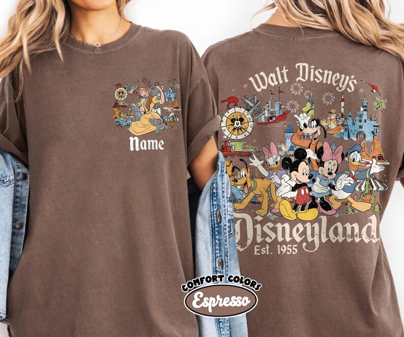 Peut inclure: T-shirt marron avec un motif Disney. L'avant pr&eacute;sente un dessin anim&eacute; et le mot "Name". Le dos affiche des personnages Disney et les mots "Walt Disney's Disneyland Est. 1955". Le t-shirt est de couleur Espresso.
