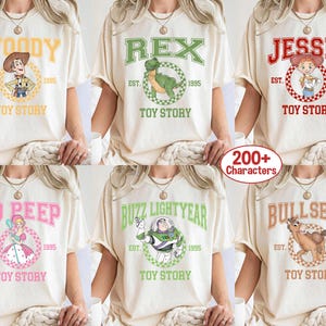 Pu&ograve; includere: T-shirt color crema con personaggi di Toy Story: Woody, Rex, Jessie, Bo Peep, Buzz Lightyear e Bullseye. Ogni maglietta presenta il nome del personaggio, il testo "Toy Story" e l'anno "1995" in un design circolare.