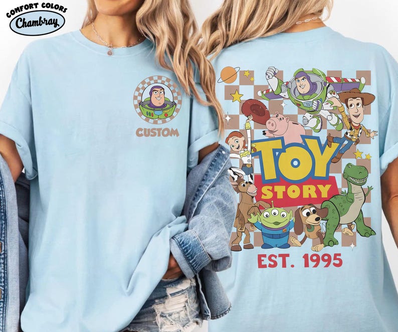 Puede incluir: Camiseta azul claro con un gr&aacute;fico de Buzz Lightyear en la parte delantera y un dise&ntilde;o de Toy Story en la parte trasera. El dise&ntilde;o trasero incluye varios personajes, el logotipo de Toy Story y el texto "EST. 1995". La camiseta tiene cuello redondo y mangas cortas.