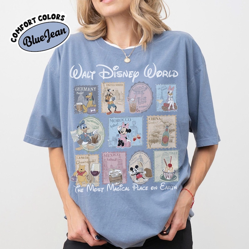 May include: Blue short-sleeve t-shirt with a Walt Disney World graphic. The graphic features Disney characters and stamps from different countries. The text "THE MOST MAGICAL PLACE ON EARTH" is at the bottom.