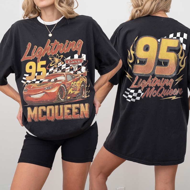 Może przedstawiać: Czarny t-shirt z motywem Zygzaka McQueena z filmu Auta. Prz&oacute;d koszulki zawiera numer 95, szachownicę i napis "McQueen". Tył koszulki r&oacute;wnież zawiera numer 95 i napis "Lightning McQueen".