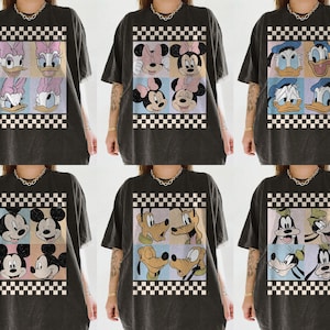 May include: Dark gray t-shirts featuring various Disney character designs. Each shirt showcases a different arrangement of characters like Daisy Duck, Minnie Mouse, Donald Duck, Mickey Mouse, Pluto, and Goofy, set against a checkered background.