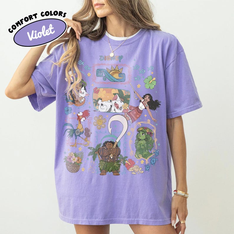 May include: A light purple Violet Comfort Colors t-shirt featuring Disney characters. The shirt has a crew neck and short sleeves. The graphic includes illustrations of characters and the word "Disney".