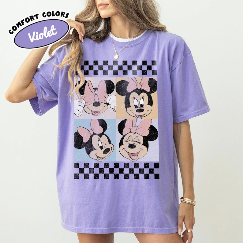 May include: Violet Comfort Colors t-shirt featuring a four-panel design with Minnie Mouse faces. Each panel has a different expression, with a black and white checkered pattern at the top and bottom. The shirt has the text "Comfort Colors" and "Violet" on the top left.