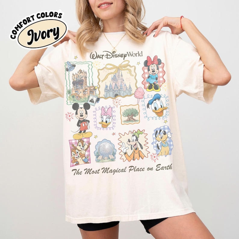 May include: Ivory-colored t-shirt featuring a colorful graphic of Disney characters and landmarks. The shirt includes the text "Walt Disney World" and "The Most Magical Place on Earth". The shirt is made of Comfort Colors material.
