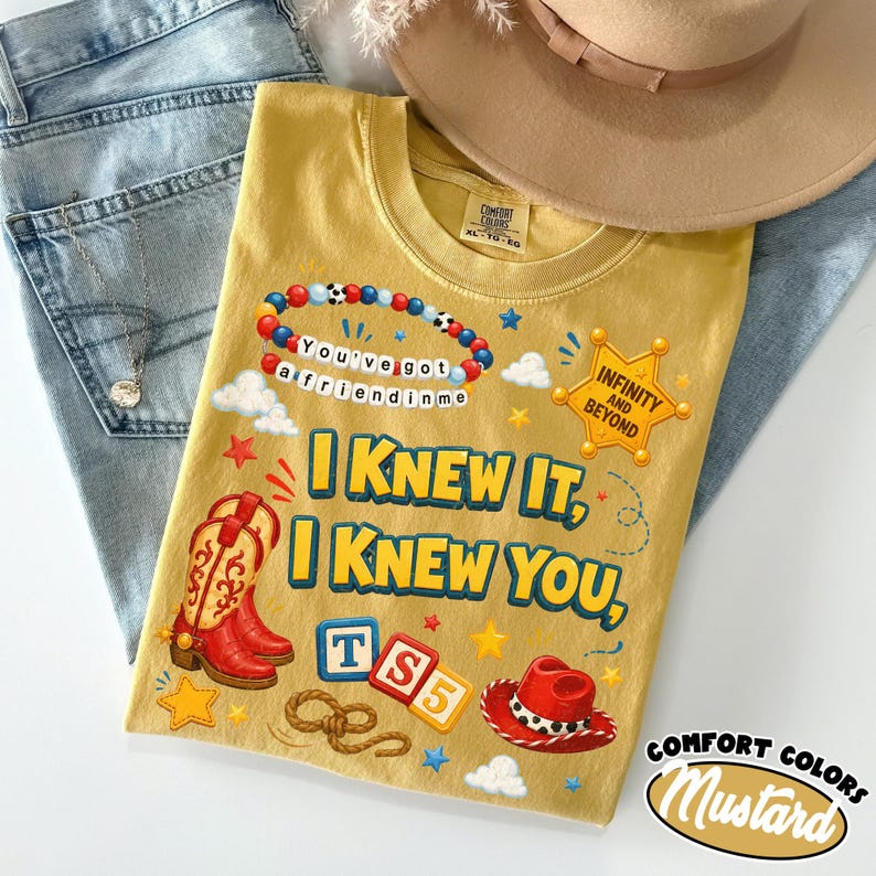 May include: A mustard yellow t-shirt featuring a graphic print with red cowboy boots, a red cowboy hat, a beaded bracelet with the text You've got a friend in me, a sheriff badge with Infinity and Beyond, and the text I KNEW IT, I KNEW YOU, TS5.