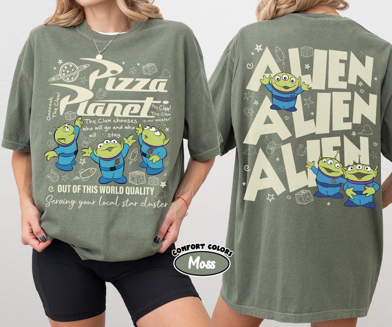 May include: Olive green t-shirt featuring the Pizza Planet logo and cartoon aliens. The front of the shirt has the text "Pizza Planet" and "Out of this world quality". The back of the shirt has the word "ALIEN" repeated three times with cartoon aliens.