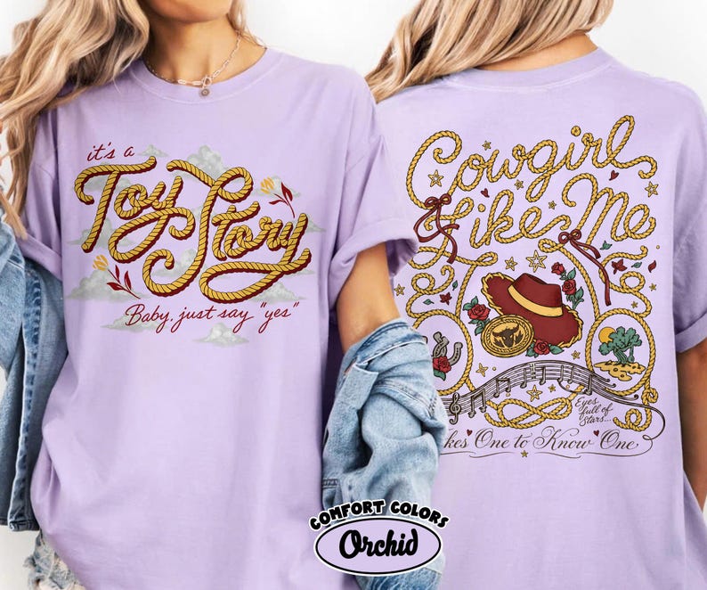 以下が含まれることがあります： ライトパープルのTシャツ。前面にはロープ風の文字で「it's a Toy Story Baby, just say "yes"」、背面には「Cowgirl like Me」の文字、カウボーイハット、音符、星が描かれたグラフィックがプリントされています。