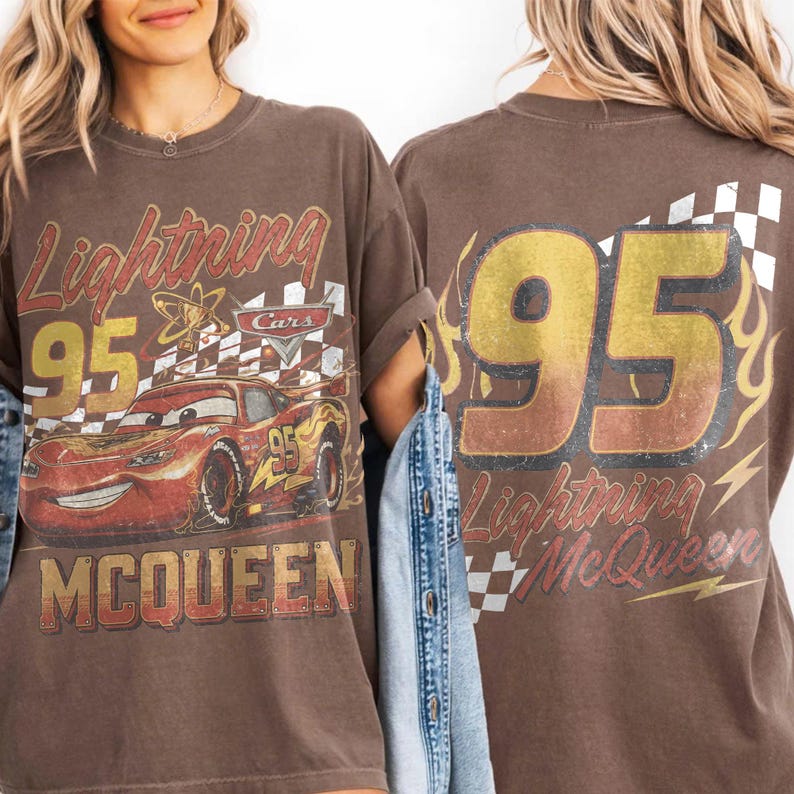 Może przedstawiać: Brązowa koszulka z Lightning McQueen z filmu Auta. Prz&oacute;d przedstawia numer 95, postać i szachownicę. Tył ma numer 95 i napis "Lightning McQueen".
