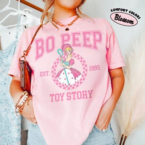 Pu&ograve; includere: Una tazza di ceramica bianca con manico nero e la scritta "But First, Coffee" in grassetto nero. La tazza &egrave; posta su uno sfondo sfocato, suggerendo un'atmosfera accogliente.