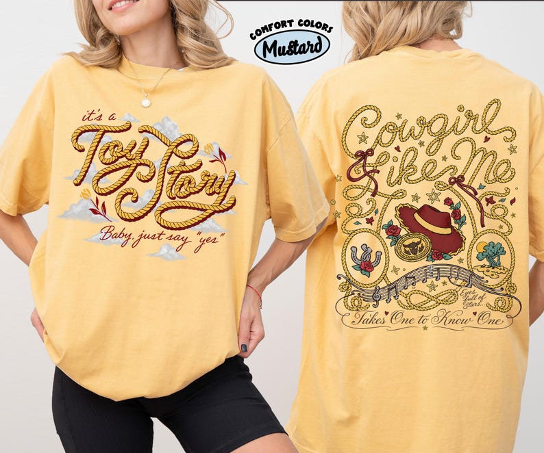 以下が含まれることがあります： マスタードイエローのTシャツ。前面にはロープ風の文字で「it's a Toy Story Baby, just say yes」と描かれ、背面には「Cowgirl like me」の文字、カウボーイハット、バラ、音符がデザインされています。