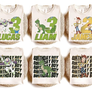 K&ouml;nnte beinhalten: Sechs cremefarbene T-Shirts mit Toy Story-Charakterdesigns. Drei Shirts zeigen eine Zahl und einen Namen: Lucas, Liam und James. Die anderen drei Shirts tragen das sich wiederholende Muster "BIRTHDAY BOY". Die Shirts liegen auf gewebten Matten.