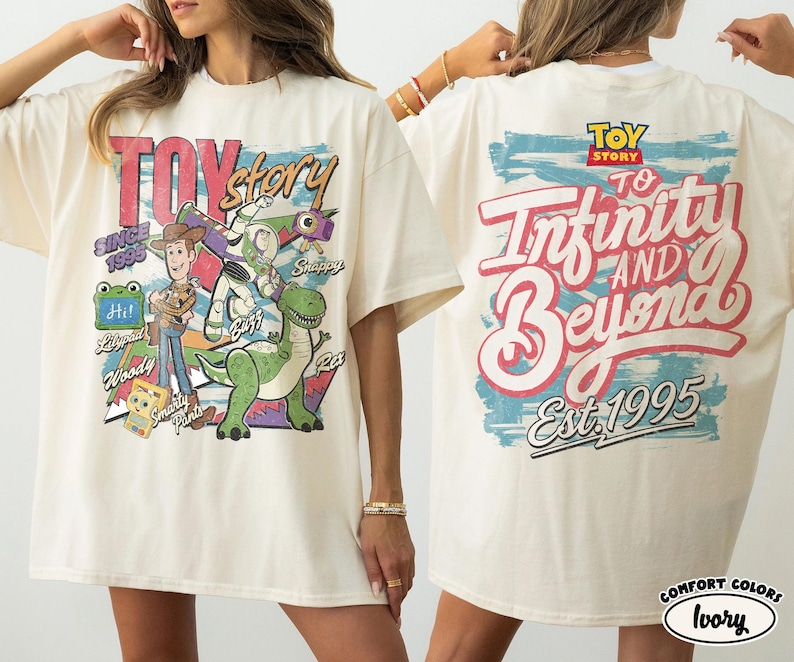 Pode incluir: Uma t-shirt cor de marfim com gr&aacute;ficos de Toy Story. A frente mostra Woody, Buzz Lightyear, Rex e texto incluindo "Toy Story", "Since 1995" e "Smarty Pants". As costas apresentam o log&oacute;tipo de Toy Story e o texto "To Infinity and Beyond Est. 1995".