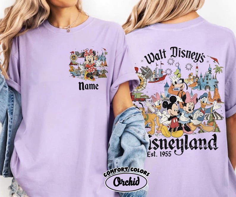 Peut inclure: T-shirt lilas Comfort Colors avec une poche avant orn&eacute;e de Minnie Mouse et du mot "Name". Le dos du t-shirt pr&eacute;sente un motif Disneyland avec Mickey Mouse, Donald Duck et d'autres personnages. Le texte "Walt Disney's Disneyland Est. 1955" est &eacute;galement visible.