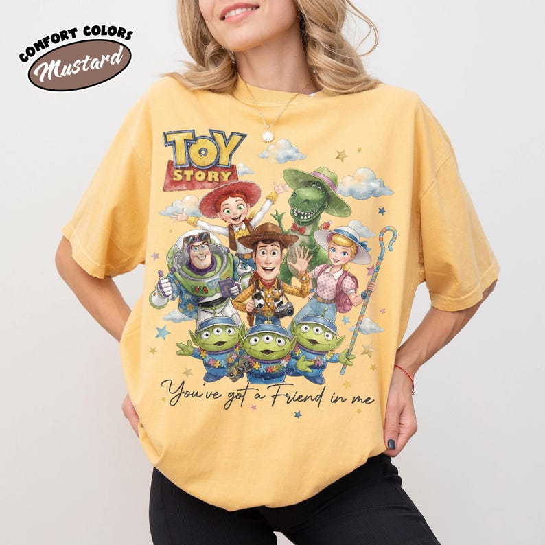 May include: Mustard yellow t-shirt with a graphic of characters from the film "Toy Story." The design includes Woody, Buzz Lightyear, and other characters, with the text "You've got a Friend in me."