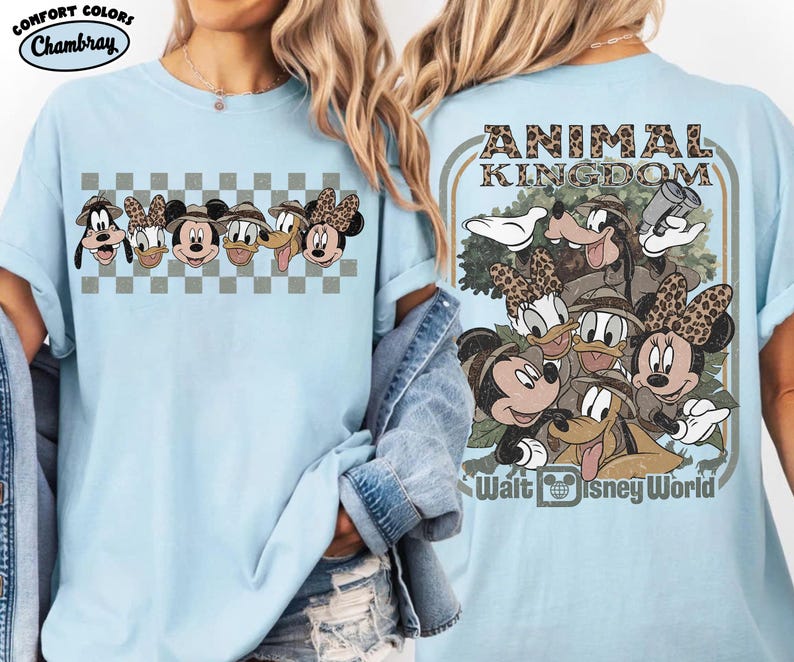 K&ouml;nnte beinhalten: Hellblaues T-Shirt mit einem Disney Animal Kingdom-Design. Auf der Vorderseite sind Gesichter von Charakteren zu sehen, w&auml;hrend die R&uuml;ckseite eine Gruppe von Charakteren mit dem Text "Animal Kingdom" und "Walt Disney World" zeigt.