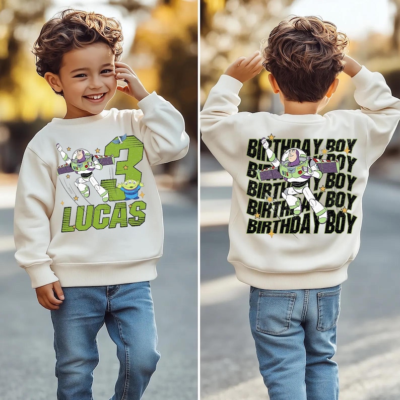 K&ouml;nnte beinhalten: Cremefarbenes Sweatshirt mit Buzz Lightyear-Design, der Zahl 3 und dem Namen "LUCAS" in Gr&uuml;n. Auf der R&uuml;ckseite befindet sich eine Buzz Lightyear-Grafik und der Text "BIRTHDAY BOY". Das Kind tr&auml;gt eine blaue Jeans.