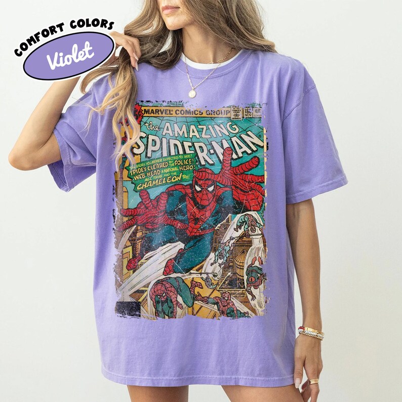 May include: A violet short-sleeve t-shirt featuring a vintage Marvel Comics The Amazing Spider-Man graphic print on the front. The design displays Spider-Man in a dynamic pose with comic book text and imagery. A violet label reads Comfort Colors.