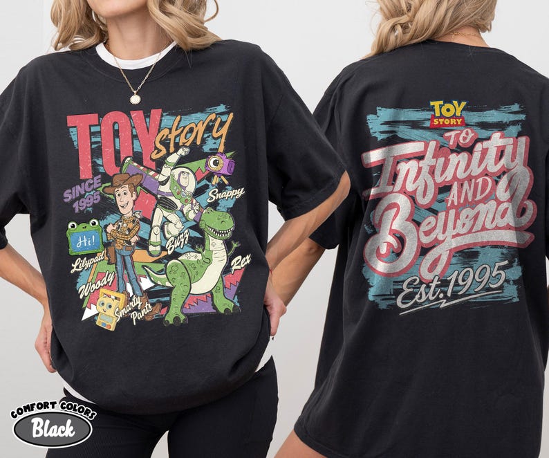 Pode incluir: Uma t-shirt preta com gr&aacute;ficos de Toy Story. A frente mostra Woody, Buzz Lightyear, Rex e outras personagens com texto incluindo "TOY story", "SINCE 1995" e nomes. As costas apresentam "TOY STORY" e "To Infinity AND Beyond Est. 1995."