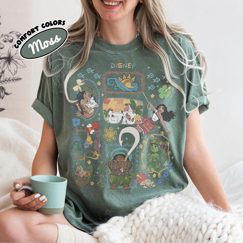May include: A moss green t-shirt with Disney characters and the word "Disney" at the top. The shirt has a crew neck and short sleeves. The words "Comfort Colors" and "Moss" are printed on a label in the upper left corner.