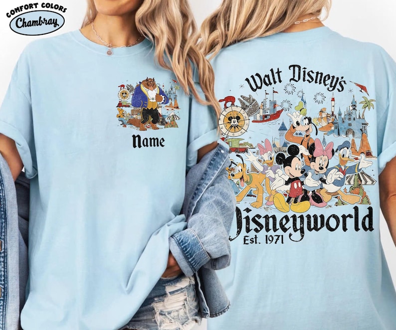 May include: Light blue t-shirt featuring a colorful graphic of Disney characters and the text "Walt Disney's Disneyworld Est. 1971" on the back. The front of the shirt has a graphic of the Beast and the word "Name".