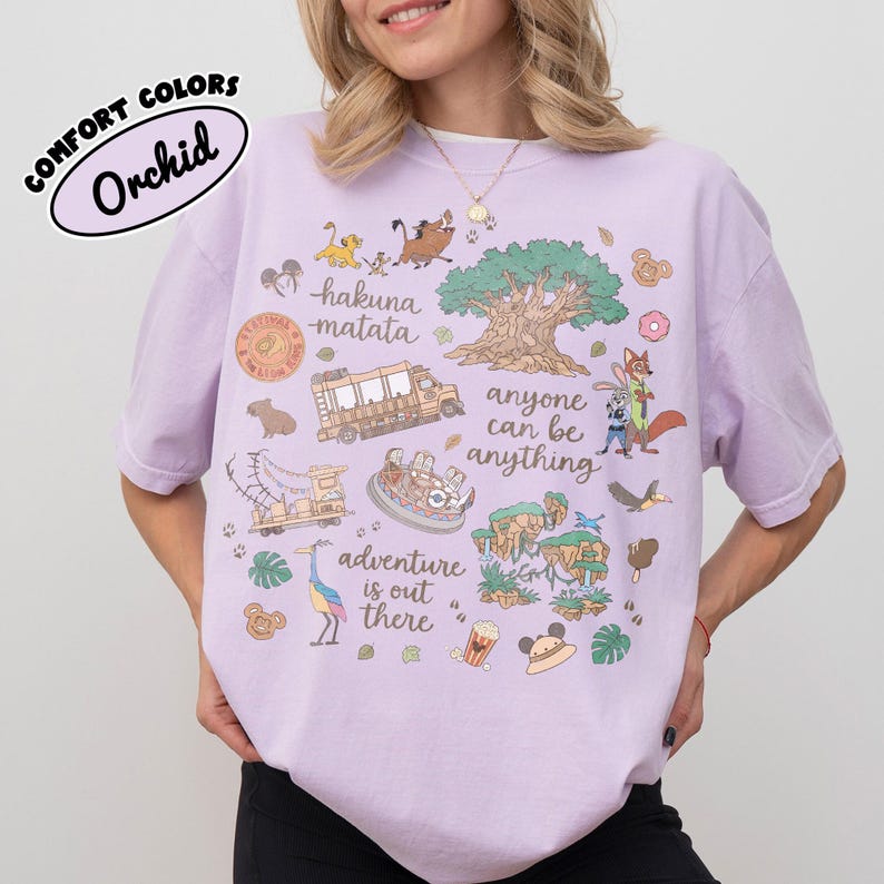 Puede incluir: Camiseta color orqu&iacute;dea con un dise&ntilde;o caprichoso con personajes de dibujos animados, un &aacute;rbol y las frases "hakuna matata" y "la aventura est&aacute; ah&iacute; fuera". La camiseta tambi&eacute;n tiene el texto "anyone can be anything".