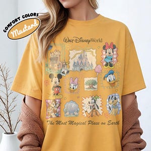 May include: Mustard-colored t-shirt with a Walt Disney World graphic. The design includes illustrations of Mickey Mouse, Minnie Mouse, Donald Duck, and other Disney characters. Text on the shirt reads "The Most Magical Place on Earth."