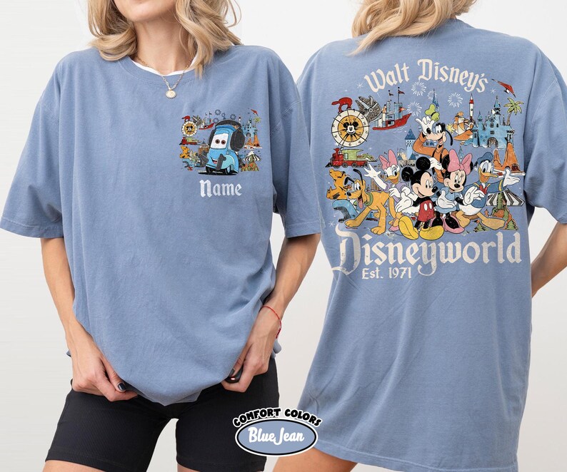 May include: A blue Comfort Colors t-shirt featuring a Disney theme. The front has a cartoon car design with the word "Name" below it. The back displays a colorful Disney World graphic with the text "Walt Disney's Disneyworld Est. 1971".