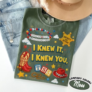 May include: An olive green t-shirt featuring a graphic print with a beaded bracelet reading You've got a friend in me, a yellow sheriff star badge with Infinity and Beyond, red cowboy boots, a red hat, and the text I Knew It, I Knew You, TS5.