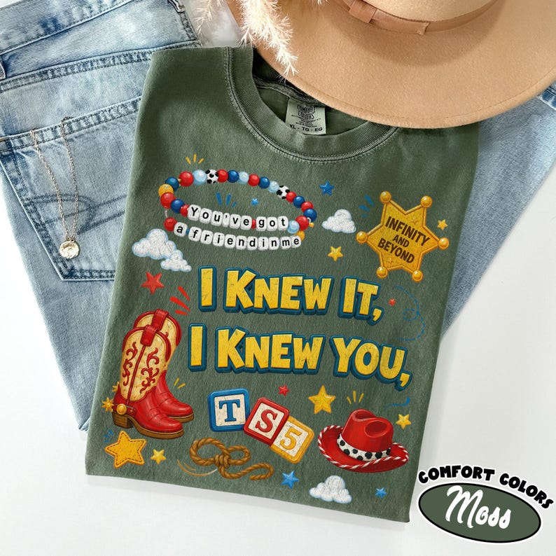 May include: An olive green t-shirt featuring a graphic print with a beaded bracelet reading You've got a friend in me, a yellow sheriff star badge with Infinity and Beyond, red cowboy boots, a red hat, and the text I Knew It, I Knew You, TS5.