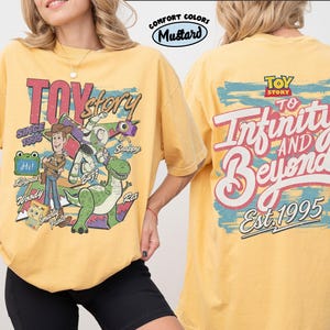 Pode incluir: Uma t-shirt amarelo mostarda com gr&aacute;ficos de Toy Story. A frente mostra Woody, Buzz Lightyear, Rex e outras personagens com o texto Toy Story Since 1995. As costas apresentam o log&oacute;tipo Toy Story e o texto To Infinity And Beyond Est. 1995.