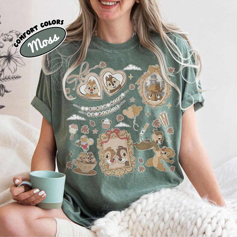 May include: Moss green t-shirt featuring Chip and Dale cartoon graphics in heart-shaped frames and other decorative elements. The shirt includes the text "Comfort Colors" and "Moss". The design is a playful and nostalgic tribute to the beloved characters.