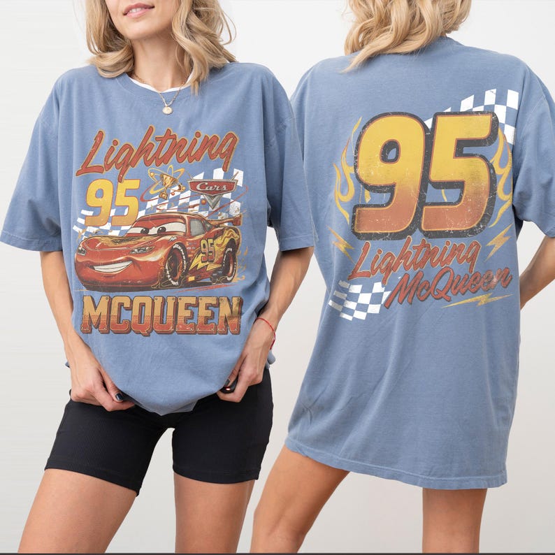 Może przedstawiać: Błękitna koszulka z Lightning McQueen z filmu Auta. Prz&oacute;d przedstawia samoch&oacute;d z napisem "Lightning 95 McQueen". Tył ma duży "95" i "Lightning McQueen" we wzorze płomieni.