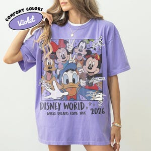 May include: Violet Comfort Colors t-shirt featuring a graphic of Disney characters including Mickey Mouse, Minnie Mouse, Donald Duck, and Goofy. The shirt has the text "Disney World 2026" and "Where Dreams Come True."
