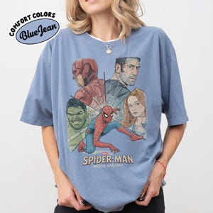 May include: Blue short-sleeve t-shirt with a graphic of Spider-Man and other Marvel characters. The shirt features the text "SPIDER-MAN BRAND NEW DAY" and the Comfort Colors logo in a blue oval.
