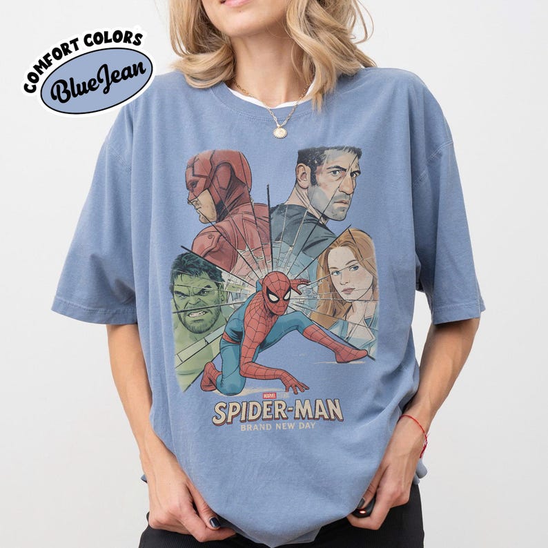 May include: Blue short-sleeve t-shirt with a graphic of Spider-Man and other Marvel characters. The shirt features the text "SPIDER-MAN BRAND NEW DAY" and the Comfort Colors logo in a blue oval.