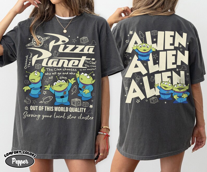 May include: Dark grey t-shirt featuring the Pizza Planet logo and three green aliens. The front of the shirt has text that reads "Pizza Planet" and "Out of this world quality". The back of the shirt has the word "ALIEN" repeated three times.